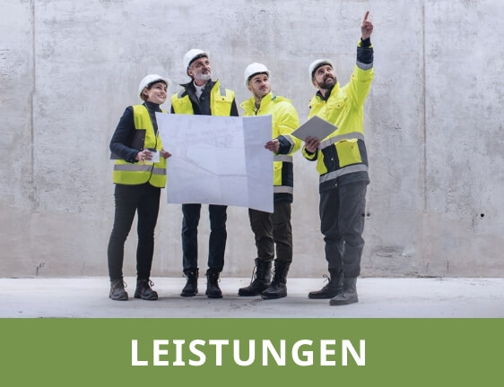 Vier Personen mit Warnkleidung und Schutzhelmen stehen in einem Rohbau und halten einen Bauplan.