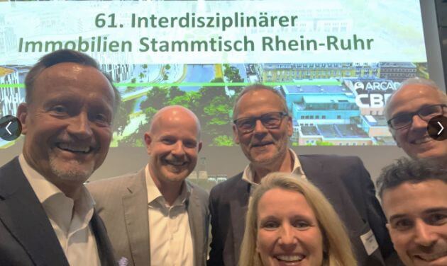 Six people in front of a screen displaying the title of the event.